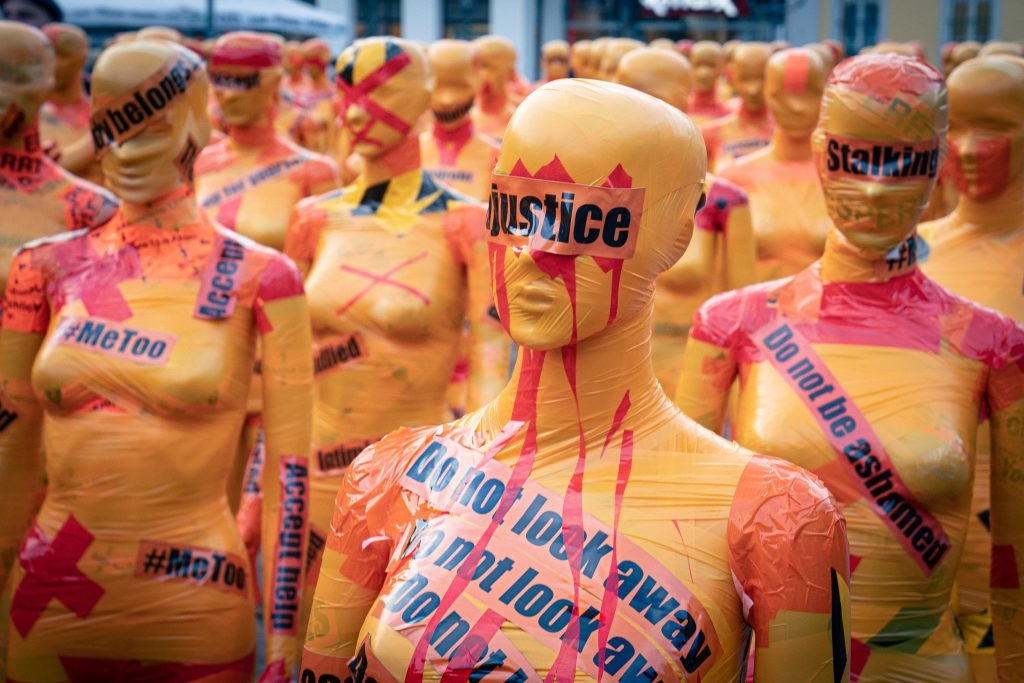 female bodied mannequins wearing different signs depicting violence against women